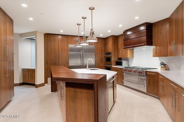 kitchen with custom range hood, decorative light fixtures, stainless steel appliances, sink, and a kitchen island with sink