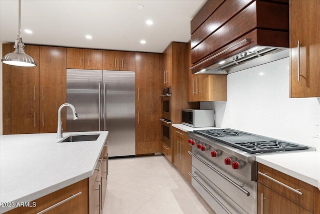 kitchen with appliances with stainless steel finishes, custom range hood, sink, and hanging light fixtures