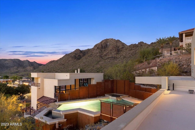 back house at dusk featuring a mountain view and an in ground hot tub