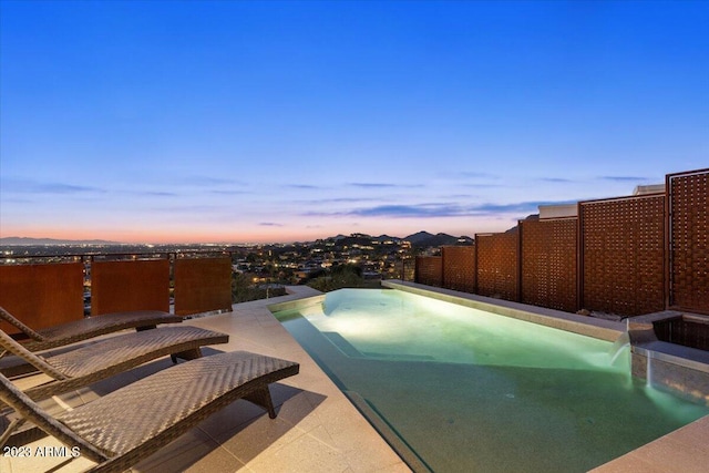 pool at dusk featuring a patio area and pool water feature