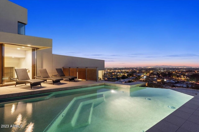 pool at dusk featuring a patio area