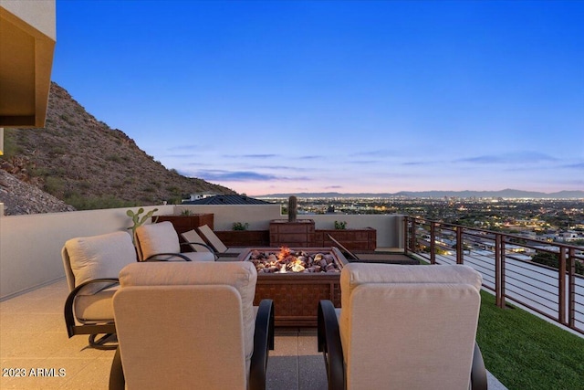 patio terrace at dusk featuring a balcony and a fire pit