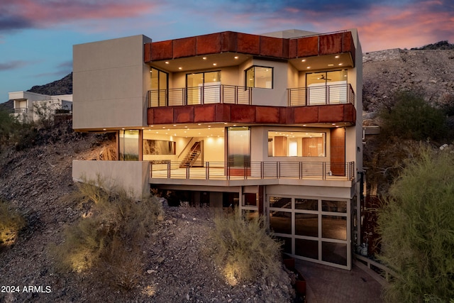 back house at dusk featuring a balcony and a mountain view