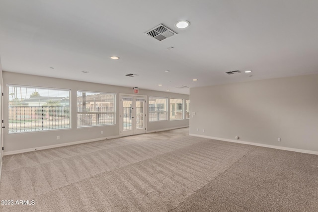 carpeted spare room featuring french doors and a healthy amount of sunlight