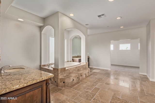 bathroom featuring vanity and tiled tub