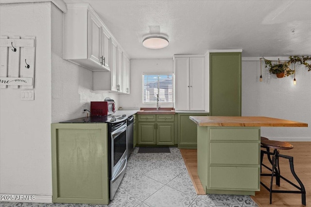 kitchen featuring green cabinetry, electric stove, white cabinets, a sink, and a kitchen island
