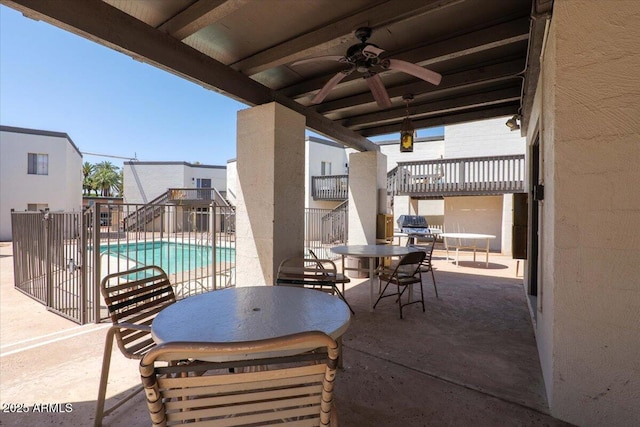 view of patio / terrace featuring stairway, ceiling fan, a community pool, outdoor dining area, and fence