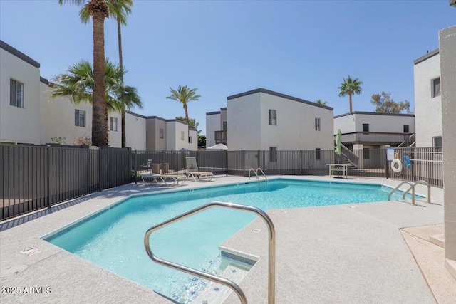 community pool featuring a patio, fence, and a residential view