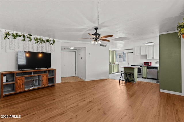 unfurnished living room featuring baseboards, a ceiling fan, and light wood-style flooring