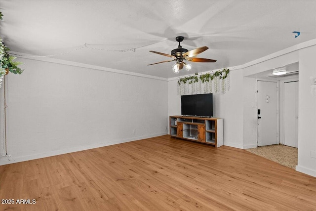 unfurnished living room featuring a ceiling fan, wood finished floors, baseboards, and ornamental molding
