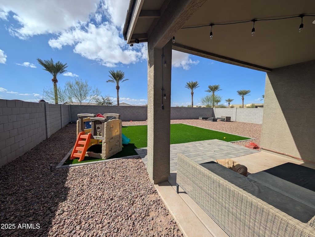 view of playground with a patio area and a fenced backyard