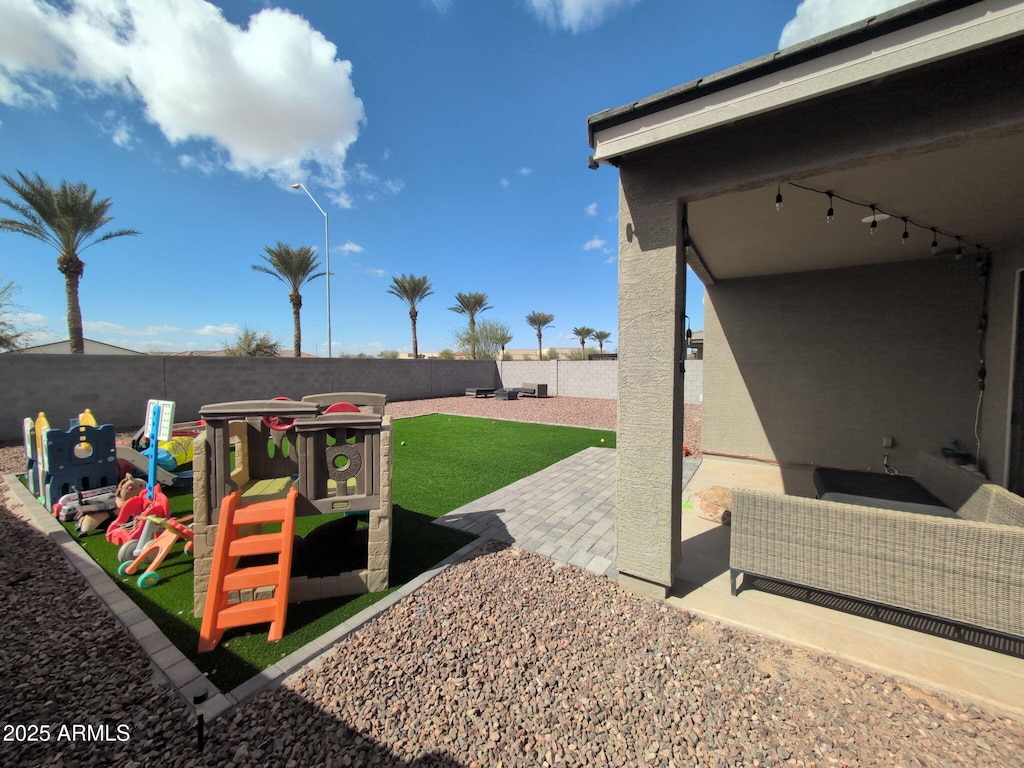 view of playground featuring a fenced backyard and a patio