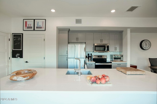 kitchen featuring gray cabinetry, sink, appliances with stainless steel finishes, and decorative backsplash