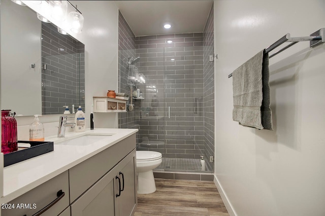 bathroom with wood-type flooring, toilet, vanity, and a shower with shower door