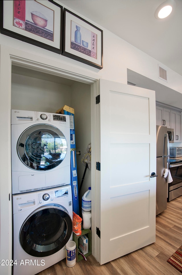 washroom featuring hardwood / wood-style floors and stacked washer and dryer