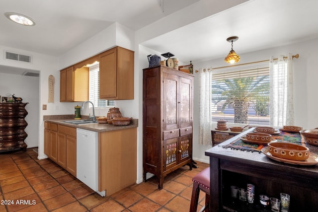 kitchen featuring light tile patterned flooring, white dishwasher, a sink, visible vents, and hanging light fixtures