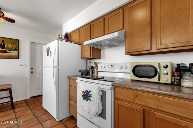 kitchen featuring brown cabinets, dark countertops, a ceiling fan, white appliances, and under cabinet range hood