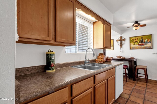 kitchen featuring ceiling fan, sink, white dishwasher, and dark tile patterned flooring