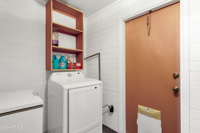 laundry room featuring brick wall and washing machine and dryer