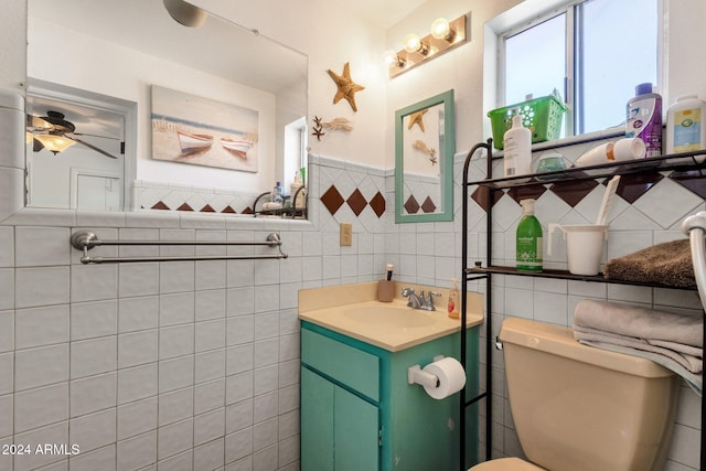 bathroom featuring tile walls, ceiling fan, vanity, and toilet