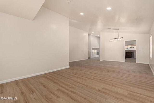 unfurnished living room with lofted ceiling, recessed lighting, wood finished floors, and baseboards