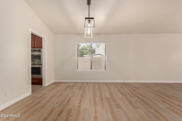 unfurnished dining area featuring vaulted ceiling, light wood-style flooring, and baseboards