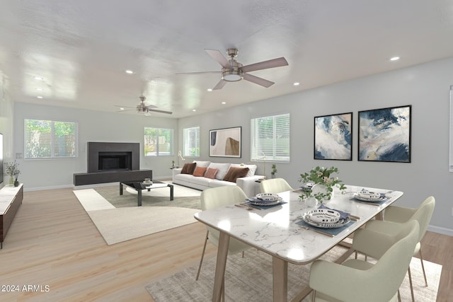 dining area featuring recessed lighting, a fireplace with raised hearth, plenty of natural light, and light wood-style flooring