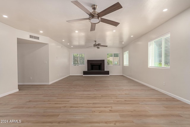 unfurnished living room with a fireplace with raised hearth, recessed lighting, visible vents, baseboards, and light wood-style floors