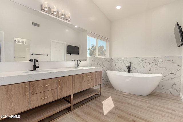 bathroom featuring wood finished floors, a freestanding tub, a sink, and visible vents