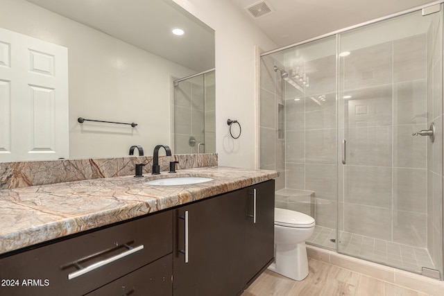 full bath featuring toilet, a stall shower, vanity, and visible vents