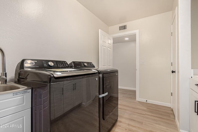 washroom featuring washing machine and dryer, light wood-style flooring, laundry area, visible vents, and baseboards