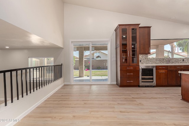 interior space featuring glass insert cabinets, beverage cooler, light countertops, and light wood-style flooring