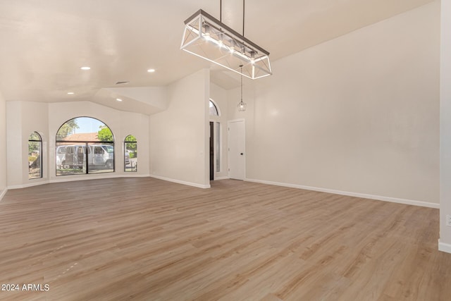 unfurnished living room with light wood finished floors, baseboards, vaulted ceiling, and recessed lighting