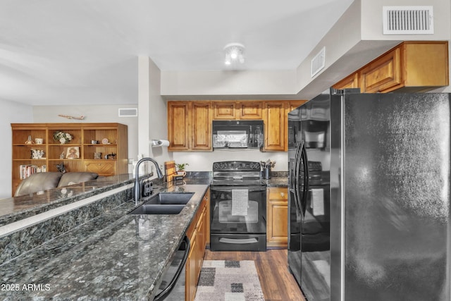 4547 E Buist Ave, Phoenix, AZ 85044 - kitchen featuring black appliances, dark wood-style flooring, dark stone counters, brown cabinetry, and a peninsula