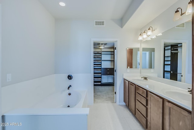 bathroom with a garden tub, double vanity, a sink, and visible vents