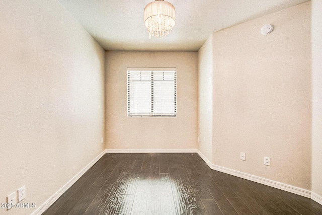 unfurnished room featuring a chandelier, baseboards, and wood finished floors