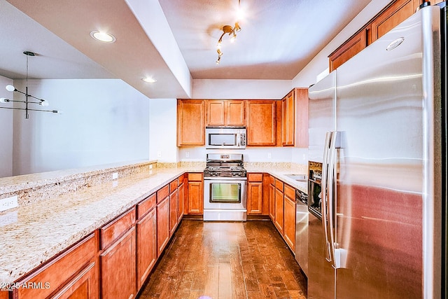 kitchen with dark wood-style floors, decorative light fixtures, stainless steel appliances, light stone countertops, and a peninsula