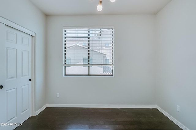 empty room with dark wood-style flooring and baseboards