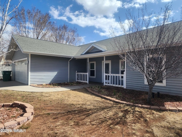 ranch-style home featuring an attached garage, a shingled roof, and a porch