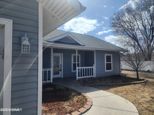 exterior space with a porch and roof with shingles