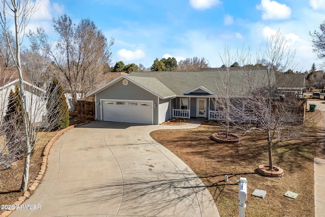 ranch-style home with a garage, concrete driveway, covered porch, and fence