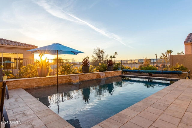 pool at dusk featuring a patio