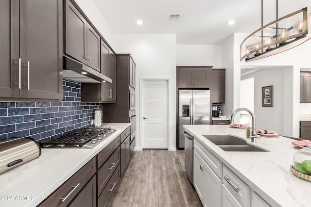 kitchen with sink, stainless steel appliances, backsplash, white cabinets, and hardwood / wood-style flooring