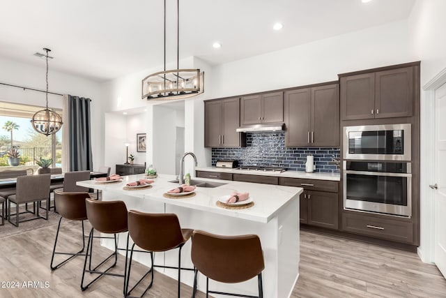 kitchen with an inviting chandelier, a center island with sink, hanging light fixtures, sink, and appliances with stainless steel finishes