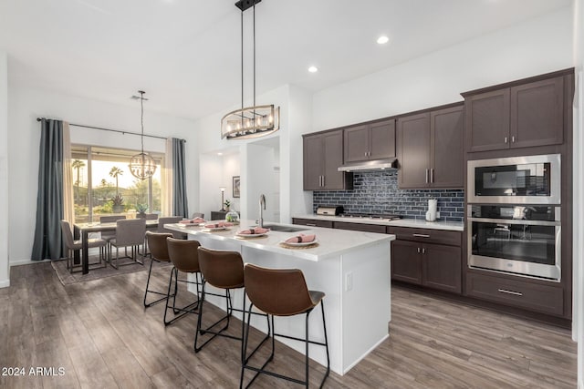 kitchen with sink, hanging light fixtures, an island with sink, a breakfast bar area, and stainless steel appliances