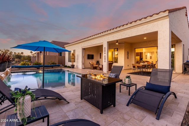 pool at dusk featuring a patio area and an outdoor fire pit