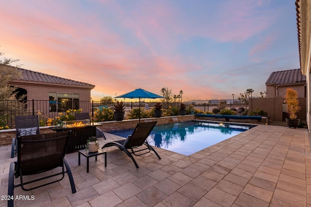 pool at dusk featuring a patio