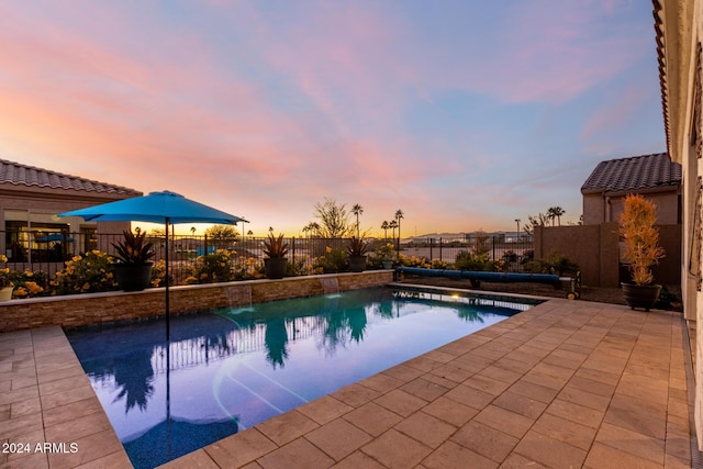 pool at dusk featuring a patio area