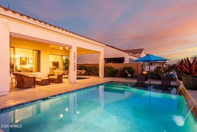 pool at dusk with a patio area, pool water feature, and an outdoor hangout area