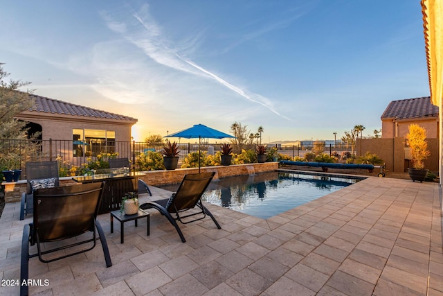 pool at dusk with a patio area